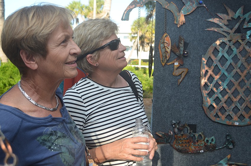 Linda Schwartz and Ursula Olson look at the art in the tent made by Detour Butterfly.