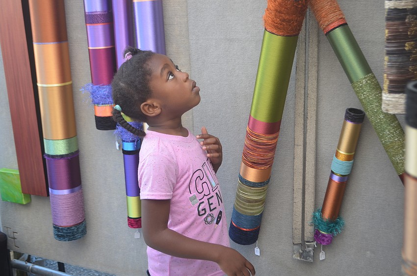 Edinam Agudu, 5, is facinated by the handmade art for sale at the festival.