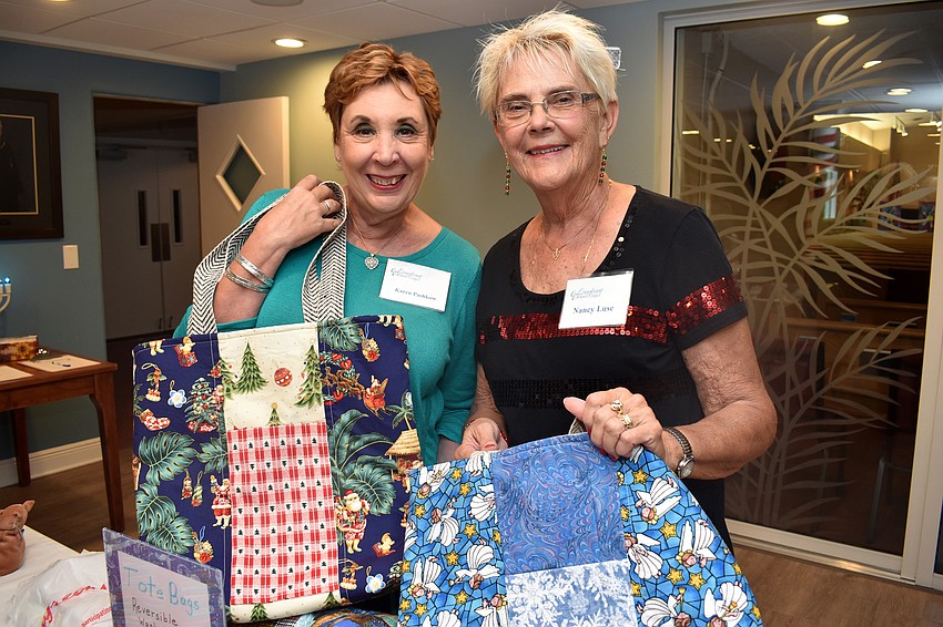 Karen Pashkow and Nancy Luse hold up tote bags Luse made.
