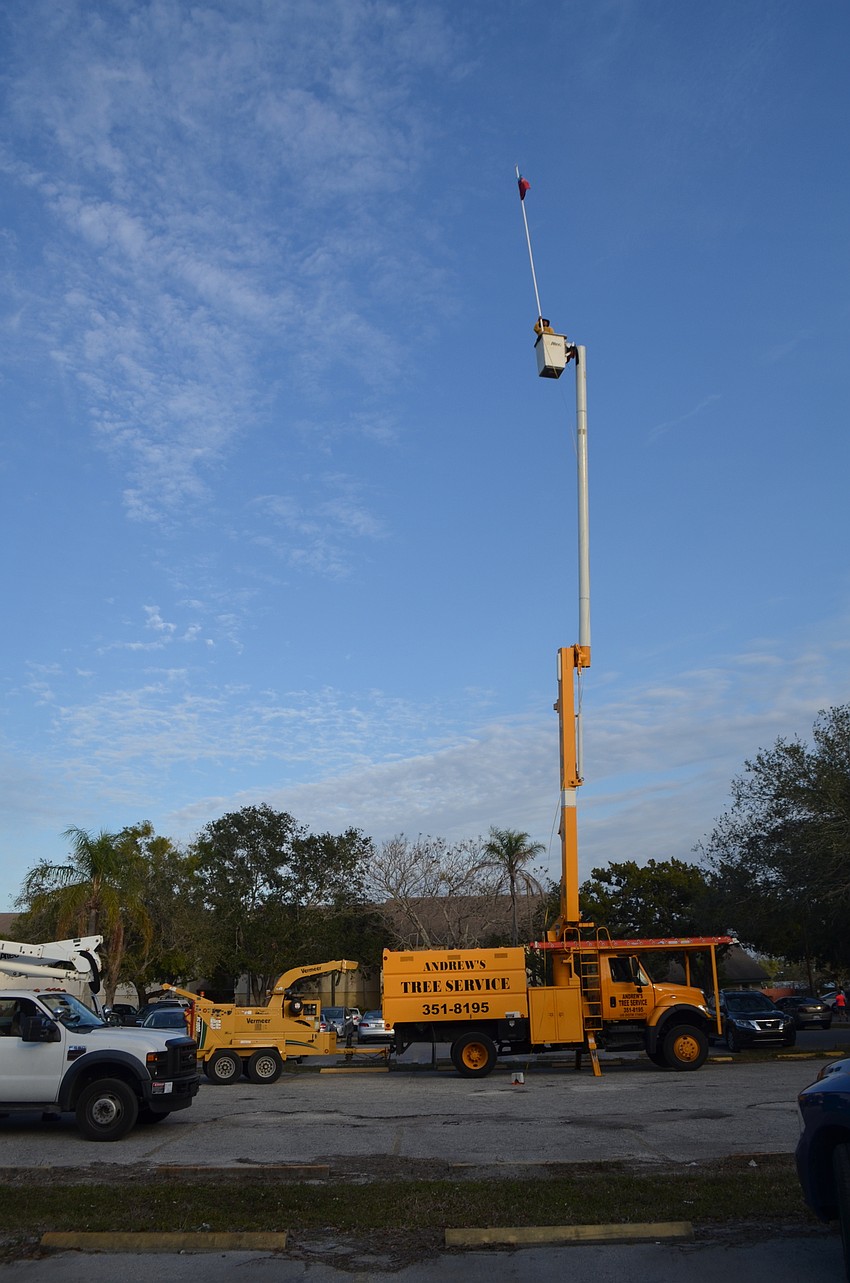 A bucket truck holds a flag 81 feet off the ground to demonstrate the height of a proposed seven-story building on the property of the Bath and Racquet Club.