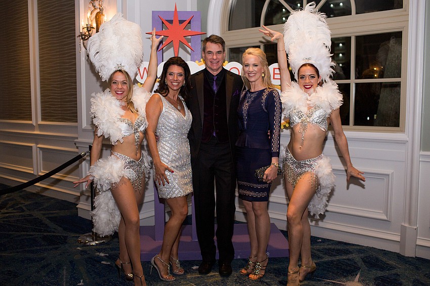 Aimee and Chris Cogan with Ariane Dart pose with Vegas showgirls March 10 at the Banyan Ball.