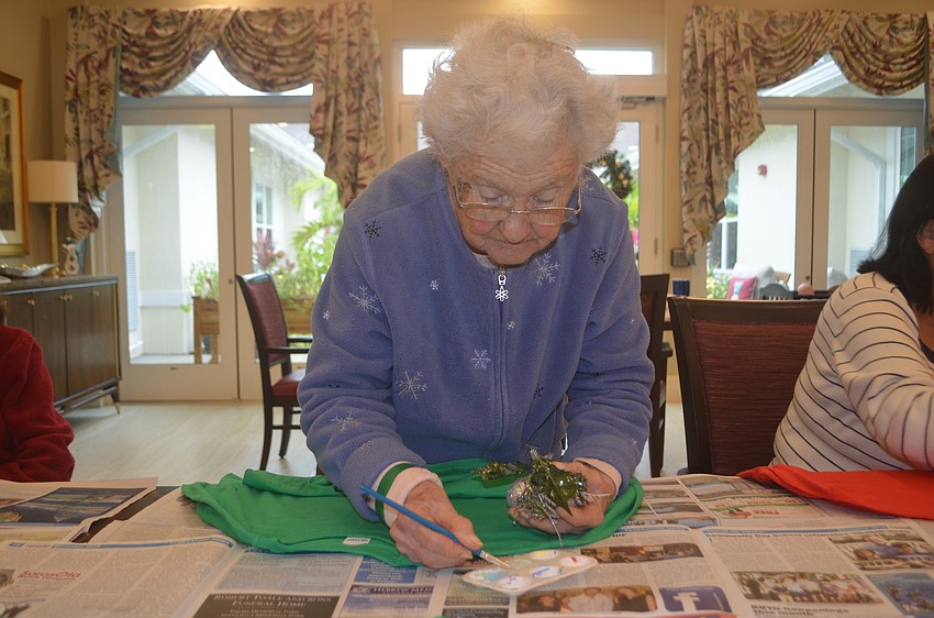 Barbara Barden uses fabric glue to fasten the main decoration piece for the sweater.