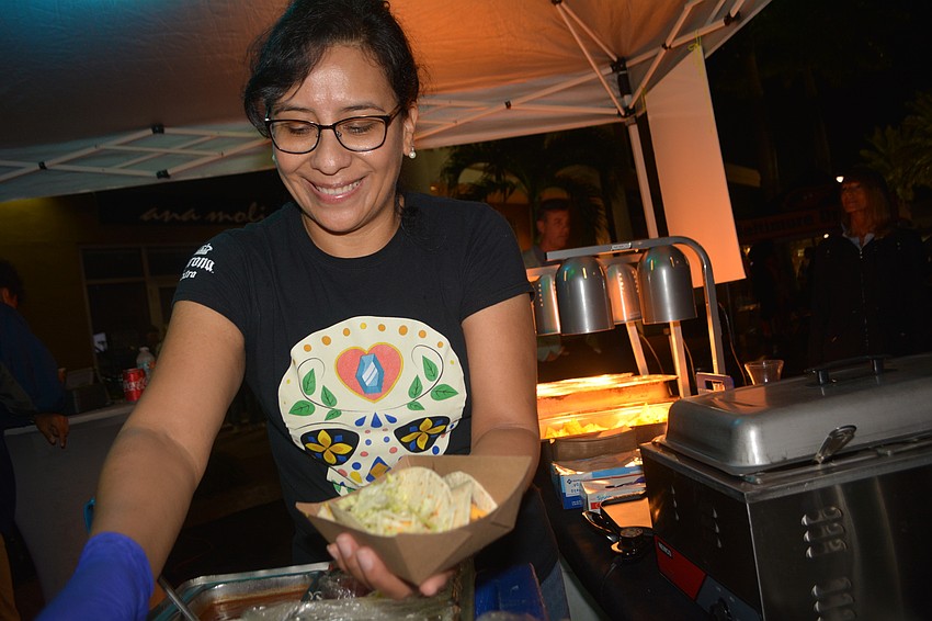 Casa Maya owner Cinthia Torrico serves up beef and chicken tacos to a customer.