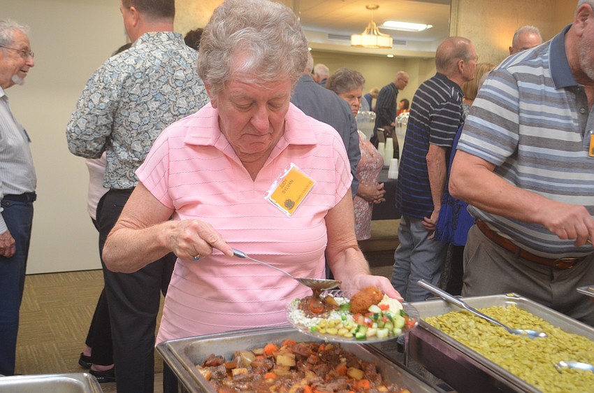 Judy Sylvan grabs herself a plate of food.