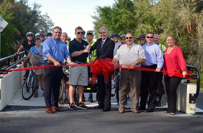 Bicyclists and trail-goers stood behind officials as they cut the ceremonial ribbon for the Laurel Road overpass.
