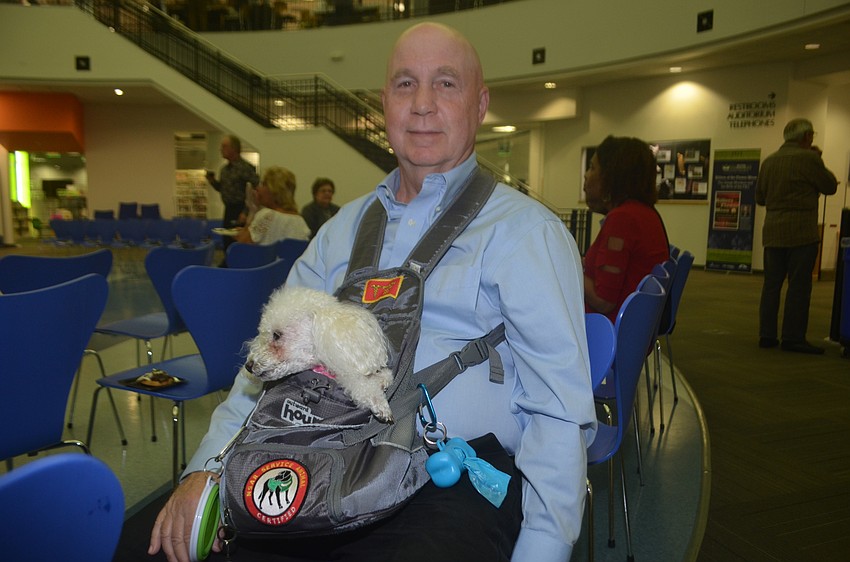 Pearl Storch, the service dog, gets to ride in the pouch carried by Carl Storch.