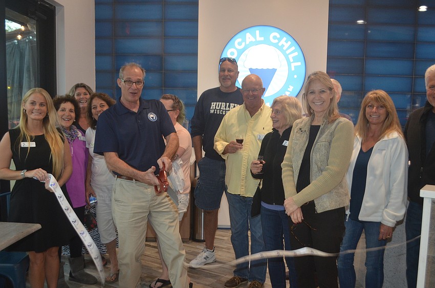 Bob Davidson, cutting the ribbon, owns Local Chill, with Suzanne Munroe (in the tan jacket)'s husband, Rick Munroe, not pictured, and John Davidson, not pictured.