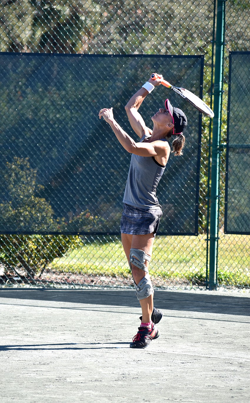 Angie Eason serves the ball during a singles match.