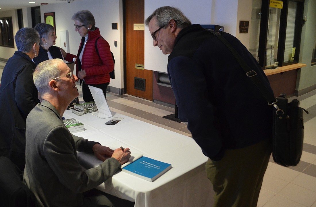 Jeff Speck, left, signs a copy of his book Walkable City Rules for city Planning Director Steve Cover at City Hall on Thursday.