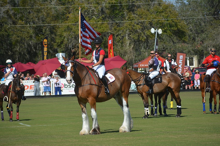 Lauren Proctor-Brown presents the flag while riding a Clydesdale.