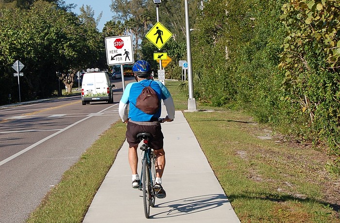 A cyclist approaches the northern end of the multi-use trail east of Gulf of Mexico Drive. To continue, riders must cross the street.