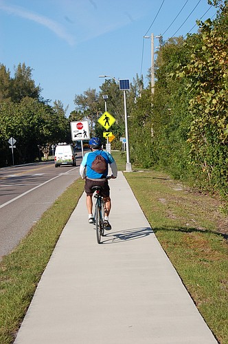 A cyclist approaches the northern end of the multi-use trail east of Gulf of Mexico Drive. To continue, riders must cross the street.