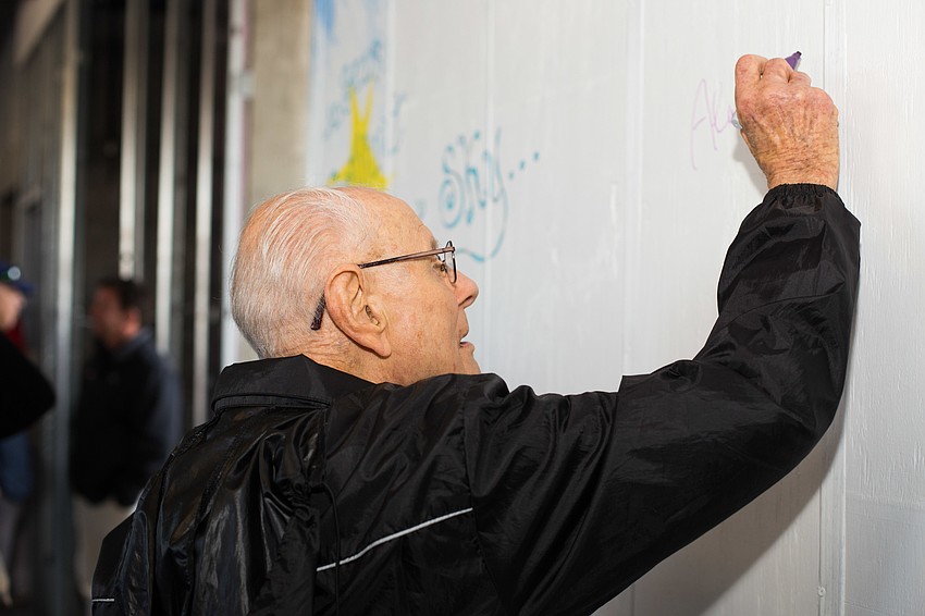 Ernie Kretzmer signs the wall with 