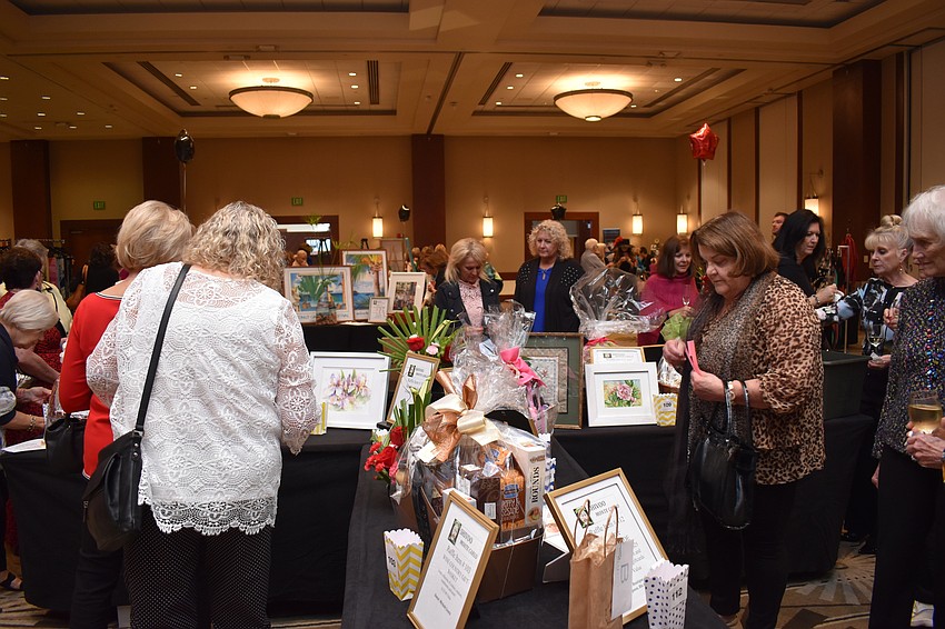 People take time before the fashion show to check out the silent auction items.