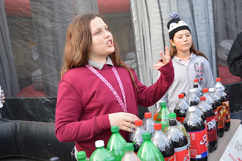 Sixth-grader Azalia Staton convinces passersby to try her carnival-style ring toss game. Each dollar earned goes toward a school field trip.