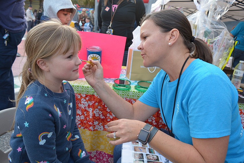 Eight-year-old Sophia Schulz, of Lakewood Ranch, chooses a cupcake paining for her face. GreyHawk Landing's Angie Kaliher, a kindergarten teacher, gets to work.