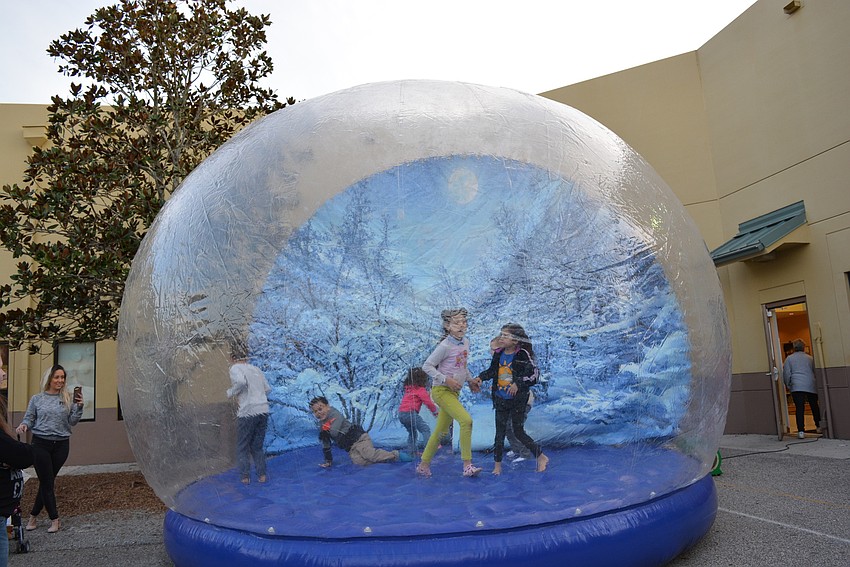 Children laugh as they realize it's fun being in an inflatable snow globe.