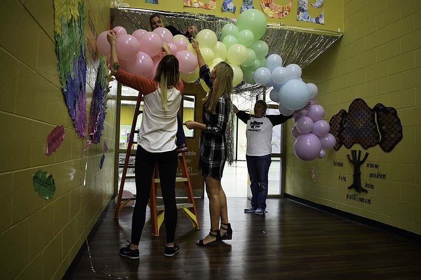 Adults work to prepare McNeal Elementary for the dance, decorating the entrance with balloons and streamers.