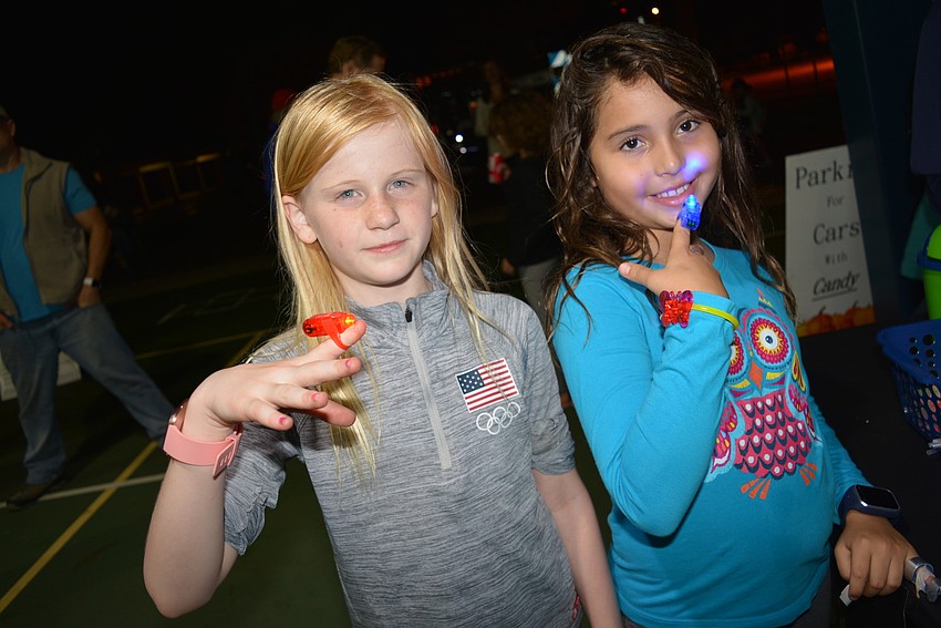 Third-graders Aubrie Conyers and Mia Freyre use their tickets to buy finger laser pointers.