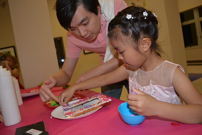 Jacky Nguyen helps his 6-year-old daughter Emma decorate a picture frame, which will hold their Sweetheart Ball photo.