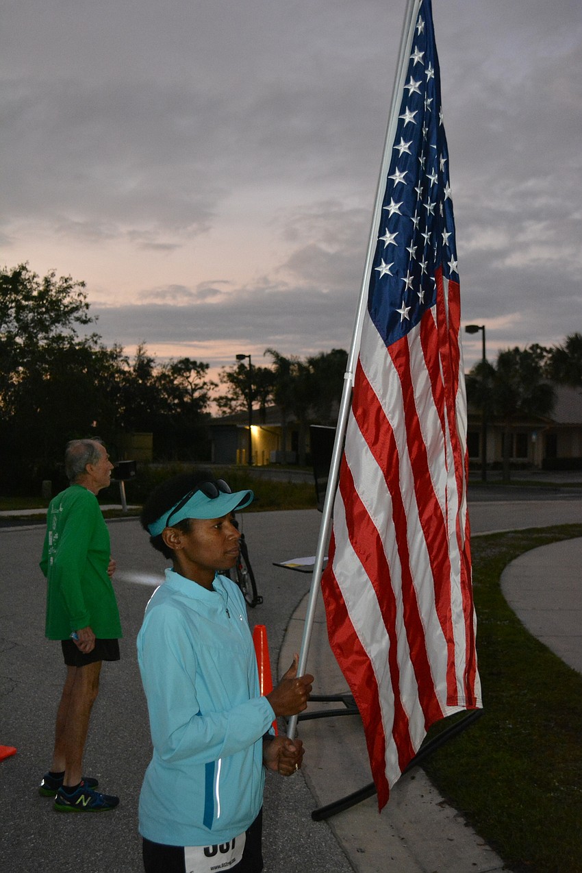 Retired Marine Regina Morris of the Lakewood Ranch Runners Club holds the flag for the National Anthem.