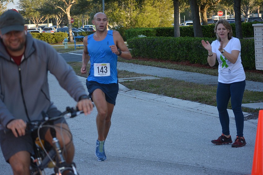 Sarasota's Matt Russell comes to the finish line as the 5K winner with support from race co-organizer Monaka Oberer