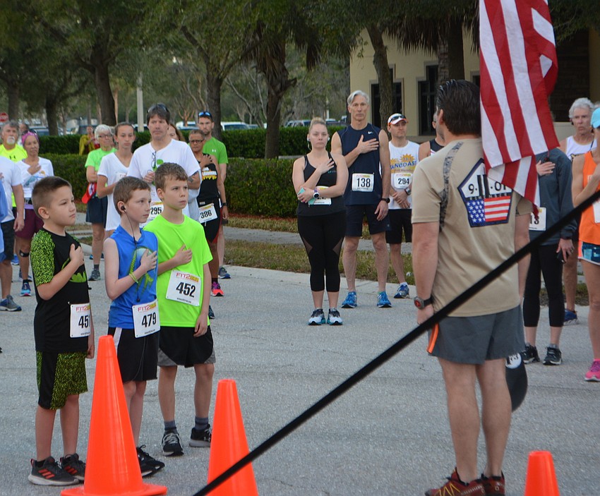 Sarasota's Paul LaBonte, 9, David LaBonte, 8, and Levi Davis, 8, pay their respect to the flag during the National Anthem.
