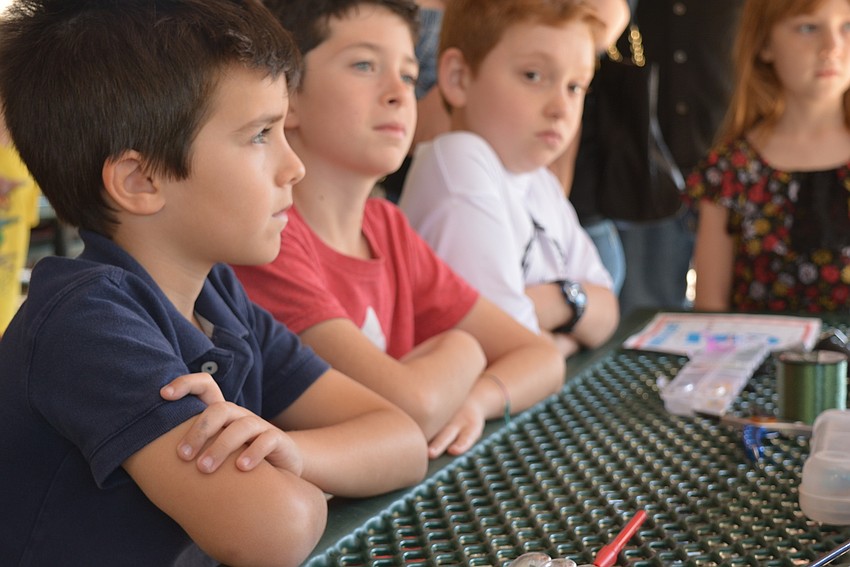 Edward and Raphael Ducrey and Bo Vaughn listen intently about how to assemble their new fishing poles.