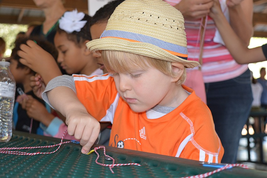 Five-year-old Mark Eubanks learns to tie a knot for his hook.