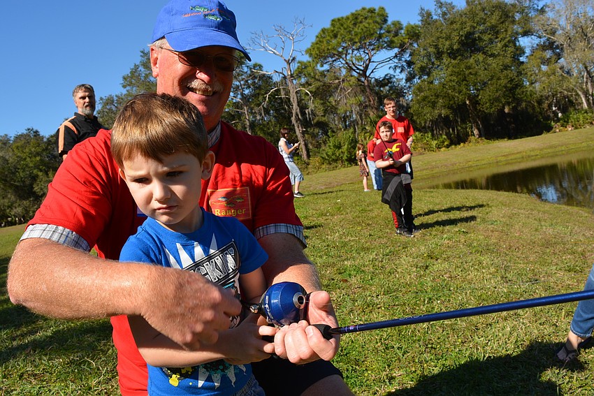 Five-year-old Jayce Neilson, of Bradenton, tries casting for the first time with the help of angler Steve Banks.