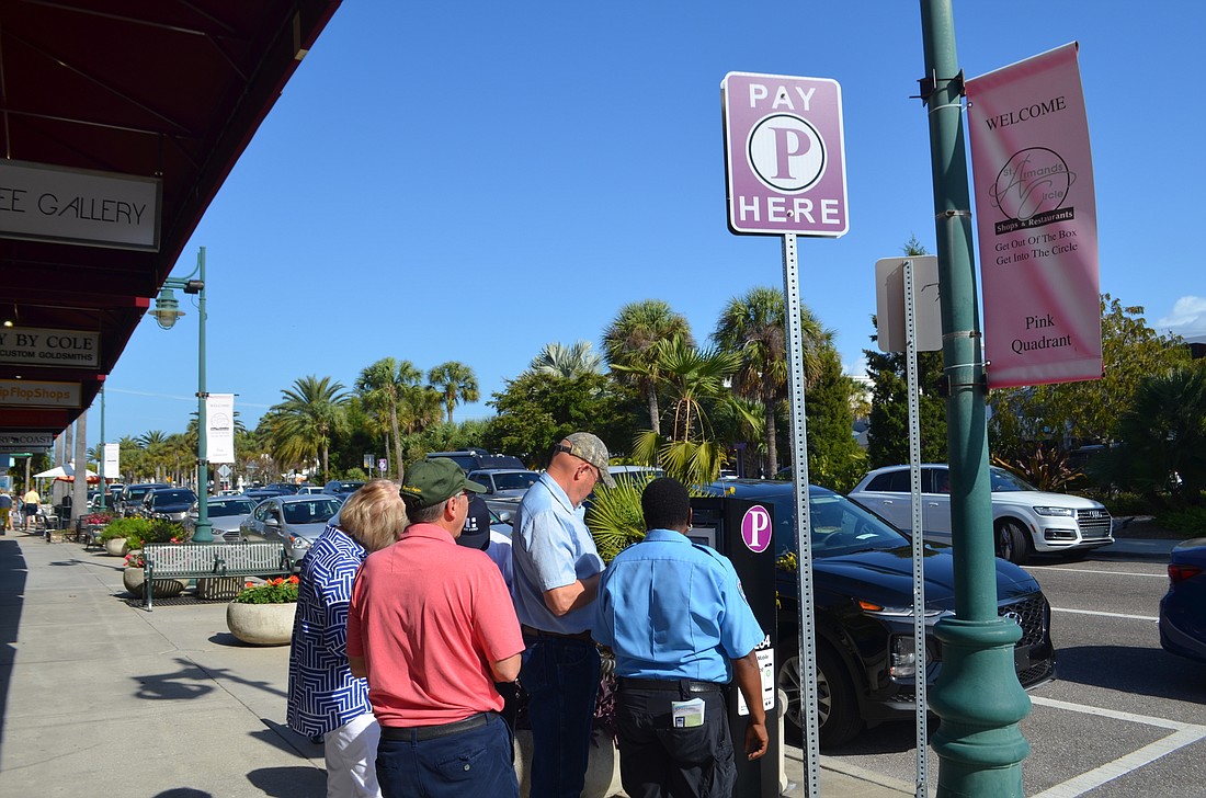 A city employee helps a group of visitors use the new parking pay stations on St. Armands Circle on Tuesday.