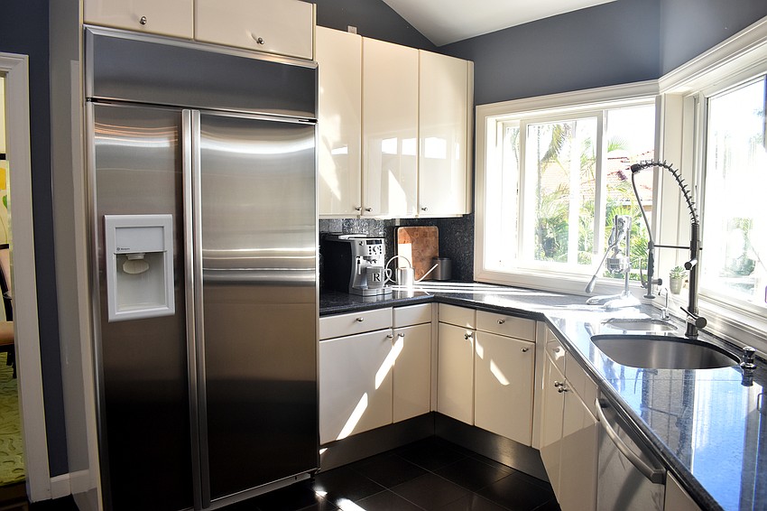 The kitchen is painted a dark blue with white cabinets. It leads to two different dining areas.