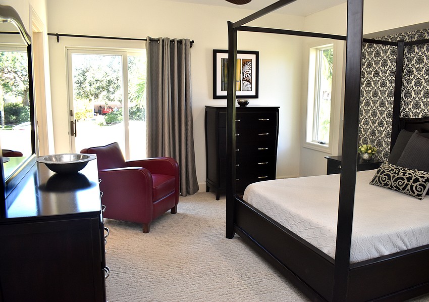 A guest bedroom features a chic black and white look with the only accent color being a purple chair.
