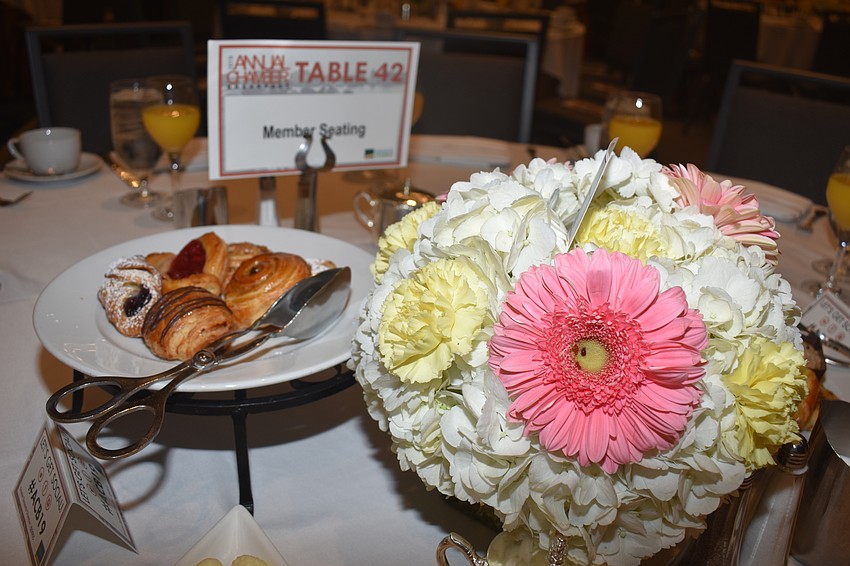 The early morning event served breakfast pastries, and tables were decorated with bright floral centerpieces.