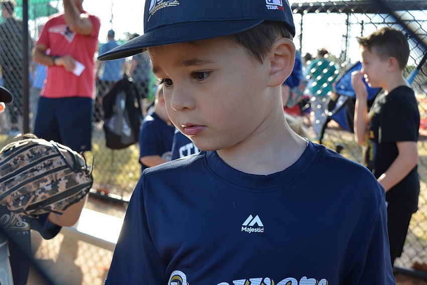 Carson Calasans checks out his dugout bucket, which holds helmets, gloves and other items.