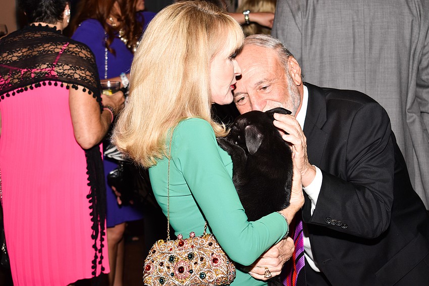 Debbie and Peter Maltese pet a puppy.