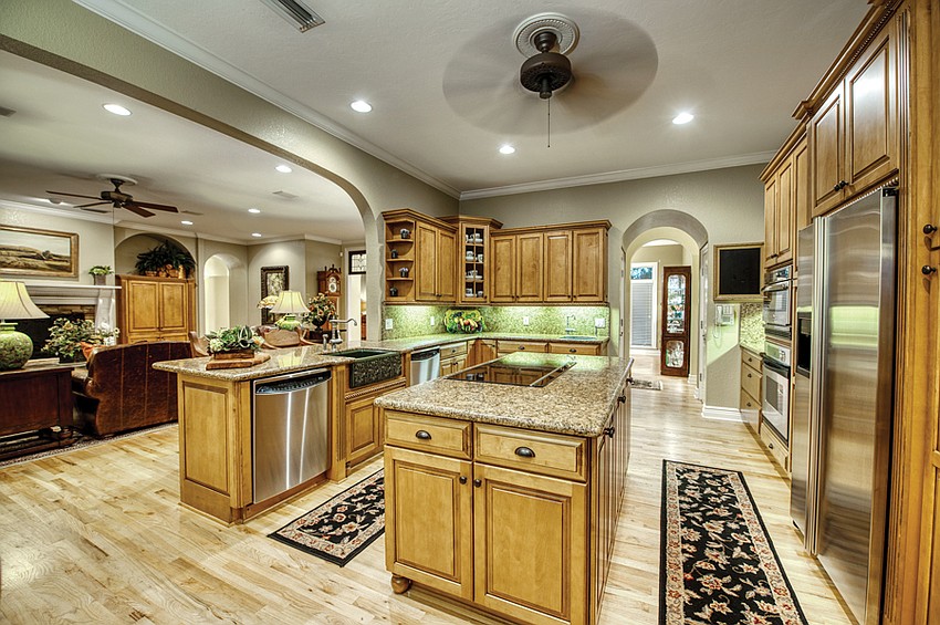 The kitchen boasts wood floors and cabinets, plus a green ceramic farmhouse sink.