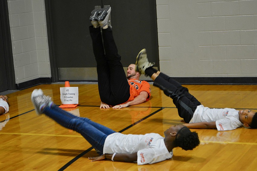Orioles pitcher Mike Wright Jr. performs leg lifts with students.