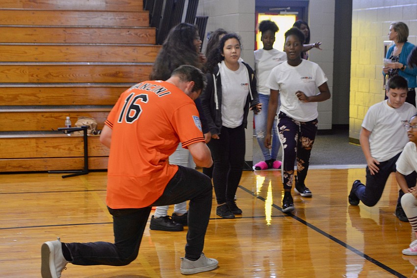 Orioles outfielder Trey Mancini performs lunges with students.
