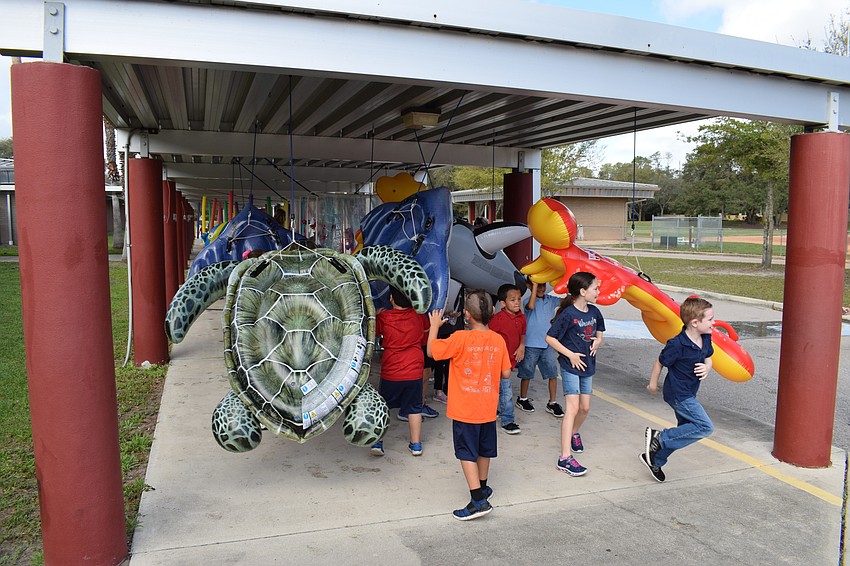 First-graders at Braden River Elementary run back and forth through the pool floats at the end of the Walk-A-Thon's route.