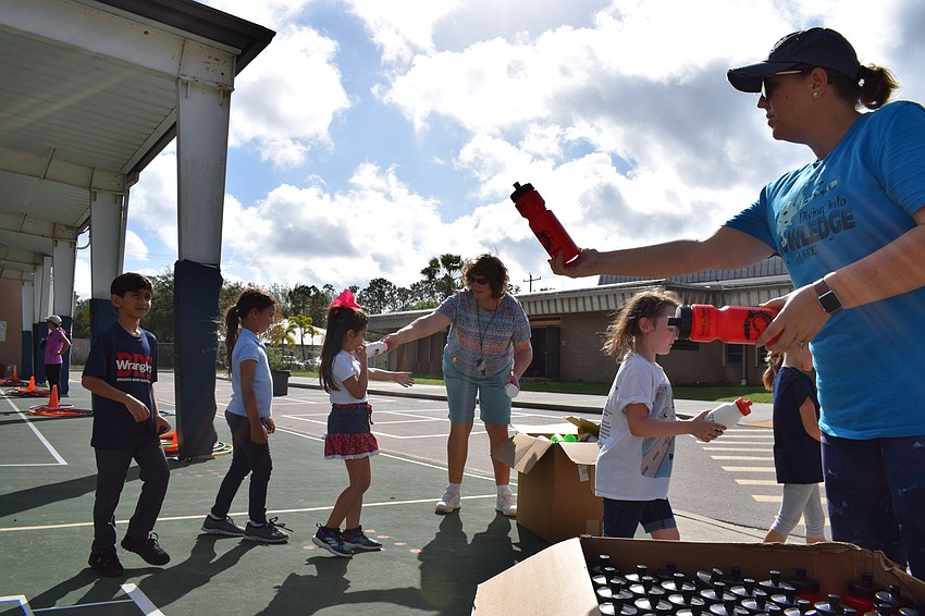 Assistant Principal Krista Franceis hands out water bottles to first-graders on their way back into the building.