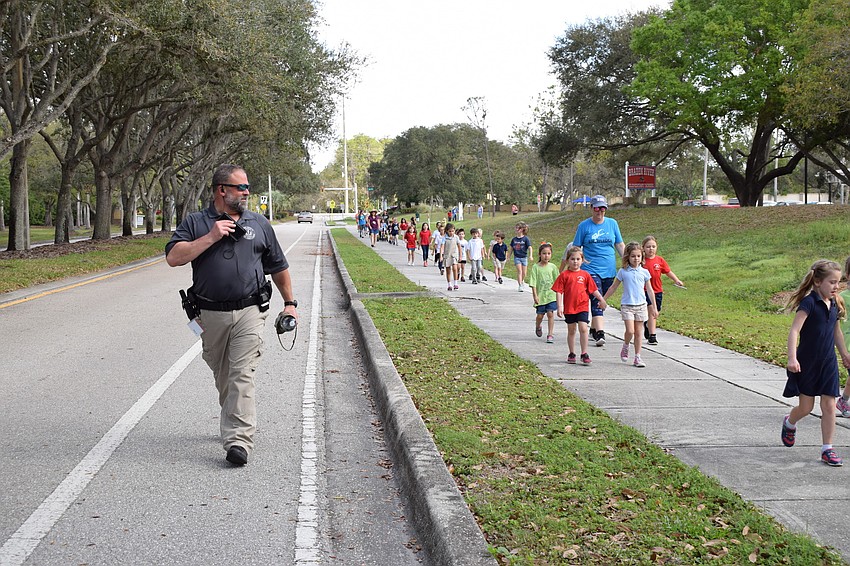 A guardian for Braden River Elementary, William Radle, walks alongside kindergarteners and warns traffic to slow down.