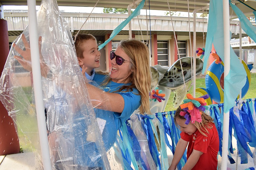 Braden River Elementary Principal Hayley Rio assists a kindergartner from Vonda Falcione's class, Lucas Dicesare, through the water tunnel.
