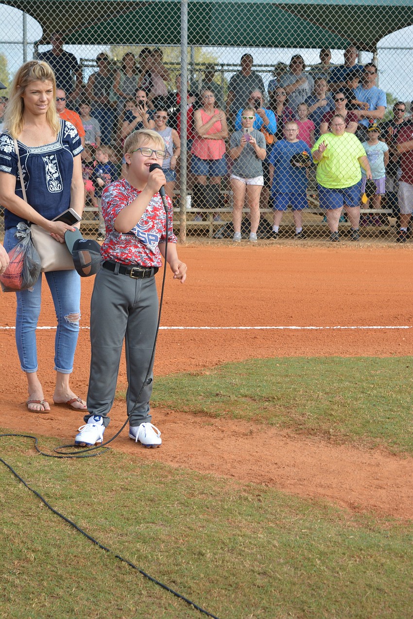 Nine-year-old Cameron Cody, with his mother Jeanne Cody behind him, sings the national anthem for the Lakewood Ranch Little League Opening Ceremony.