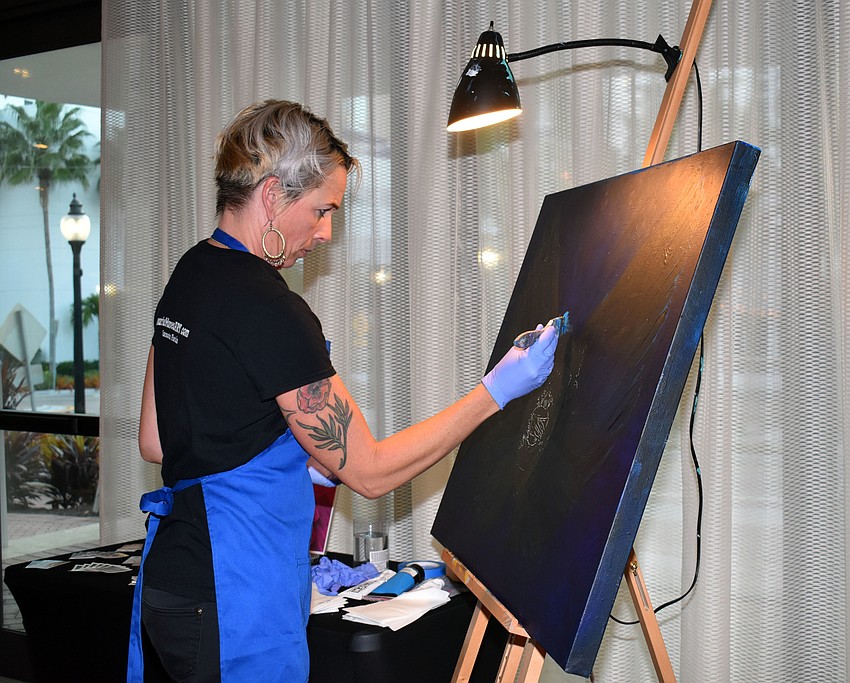 Artist Laurie Mares paints live in front of the crowd.