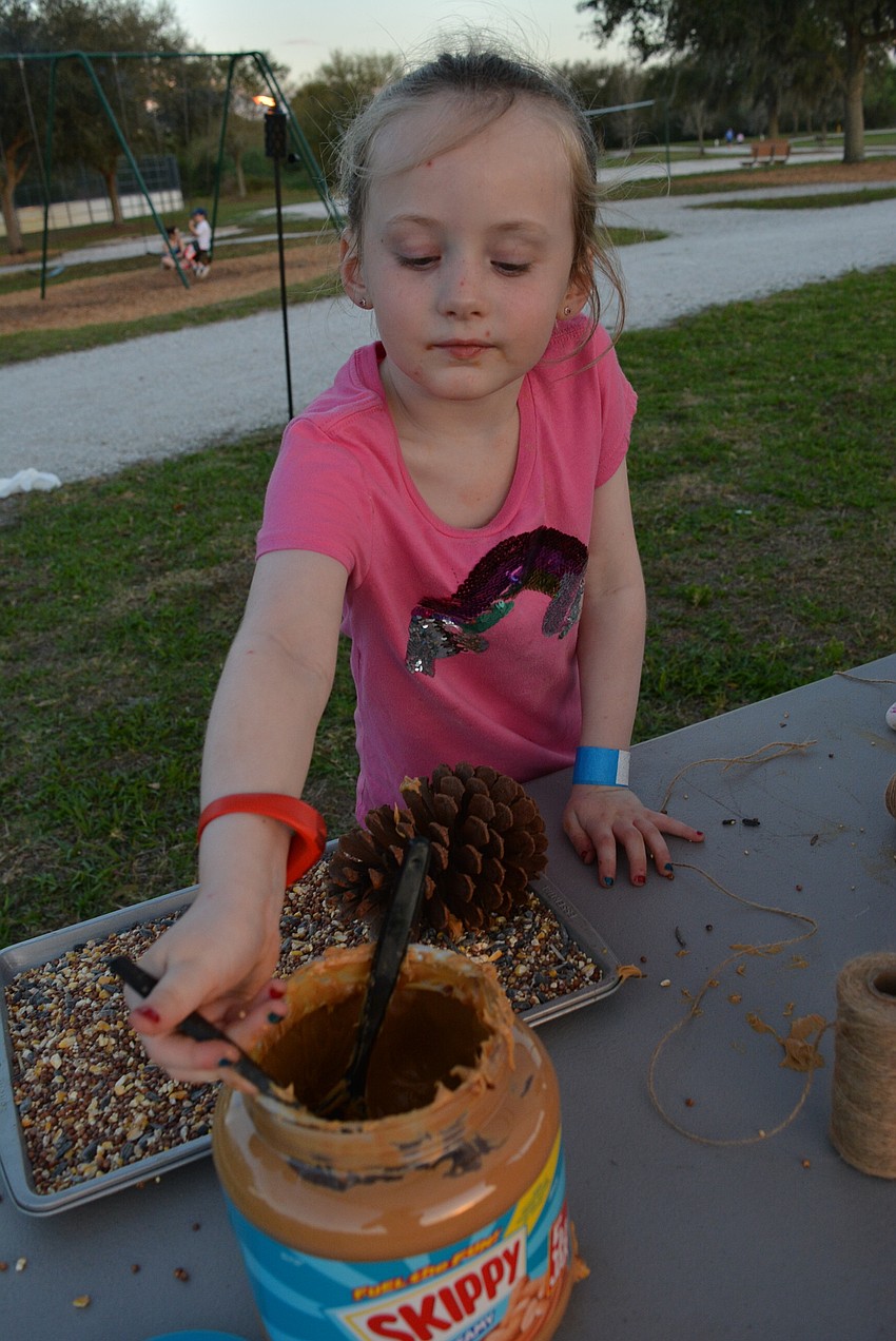 Teagan Portale, 5, makes a bird feeder with a pine cone, peanut butter and bird seed.