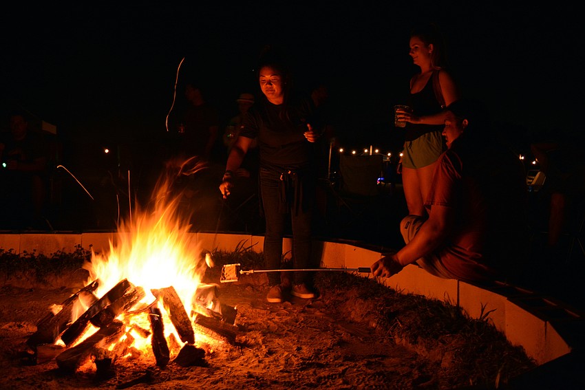 LWR Communities' Morgan Bettes roasts a marshmallow as friends Mackenzie Straley andAntonio Hernandez watch.
