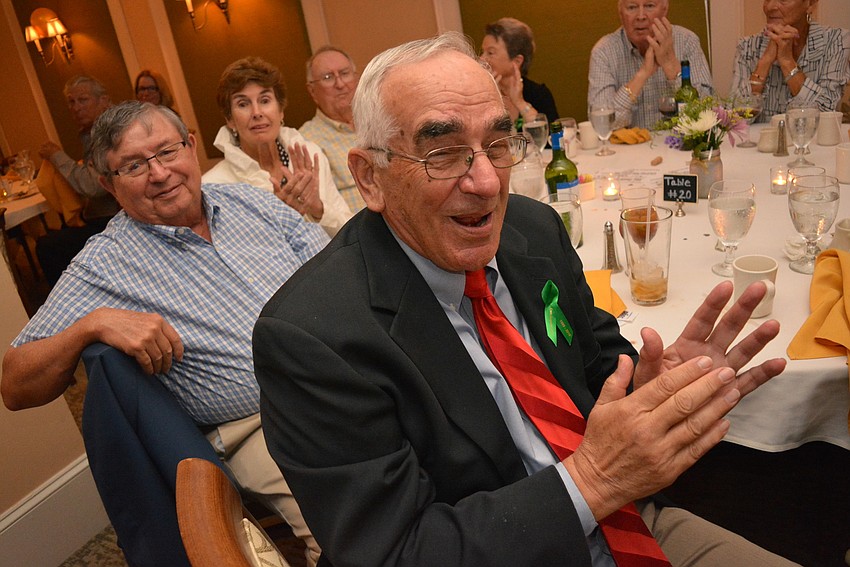 Bob Dallessandro, front, and Richard Farr, behind, clap for Tara Golf and Country Club's past golf champions, who were recognized during the celebration dinner March 2.