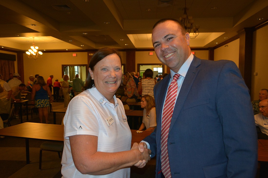Emma Piper, the tournament services manager for the Web.com Tour congratulates Synovus Vice President Kent Lane for a successful LECOM Suncoast Classic. Synovus sponsored the volunteers.