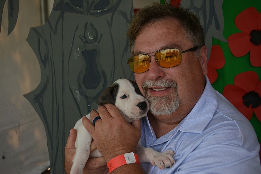 Stephen Shrewsbury shows off Scarecrow, a hound mix puppy ready to be adopted at Nate's. Shrewsbury was with the Saxs Fifth Avenue sponsor group.